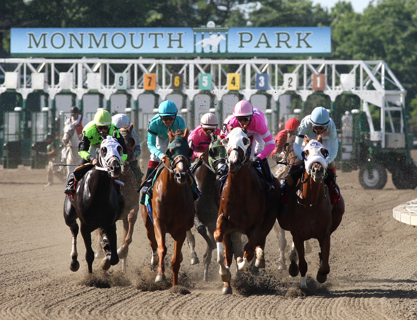 horses racing in front of Monmouth Park sign